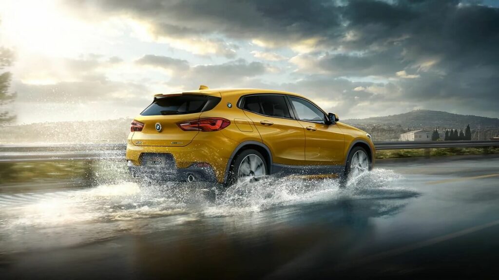 Traseira do BMW X2 2022 na cor amarela, andando sobre poça de água