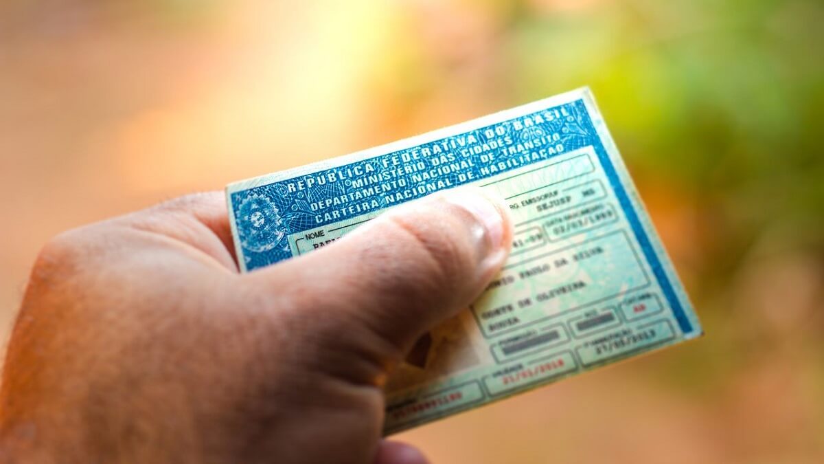 Pessoa segurando a CNH na mão habilitação