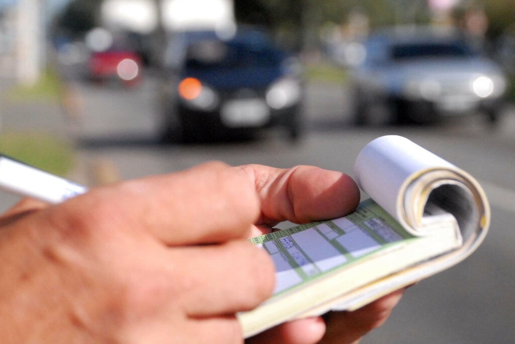 Pessoa anotando em folha de papel para recorrer de multa no Detran