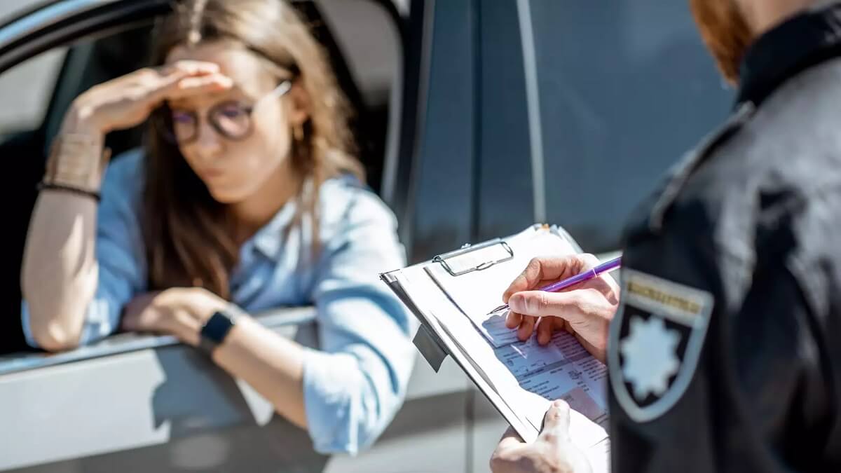 Mulher dentro do seu veículo levando multa de trânsito
