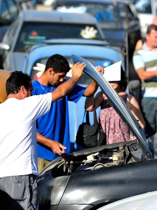 Pessoas olhando motor do carro no leilão