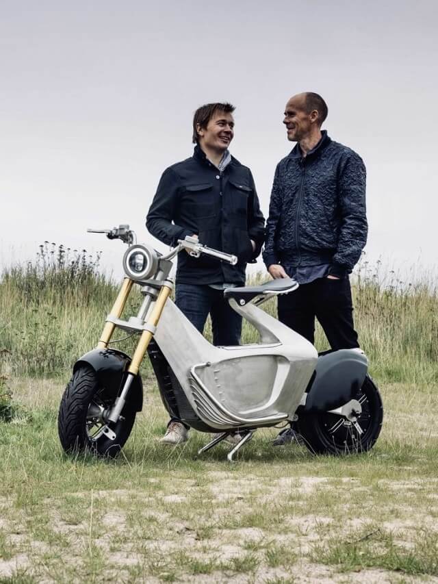 Criadores da moto elétrica Stilride SUS1 2022, estão parados na grama com a moto em frente a eles