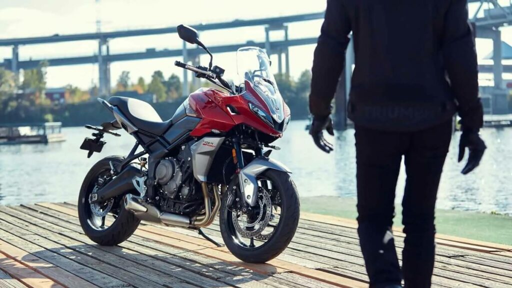 Pessoa indo em direção da Tiger Sport 660 2022 na cor vermelha, estacionada perto da água
