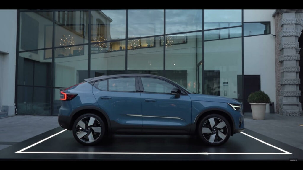 Volvo C40 azul  com uma superfície reflexiva por trás.