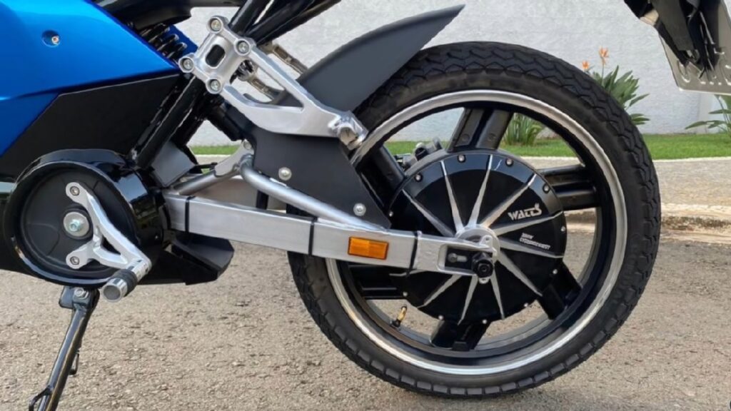 Roda da Watts W125 azul com motor de cubo em uma estrada de asfalto.