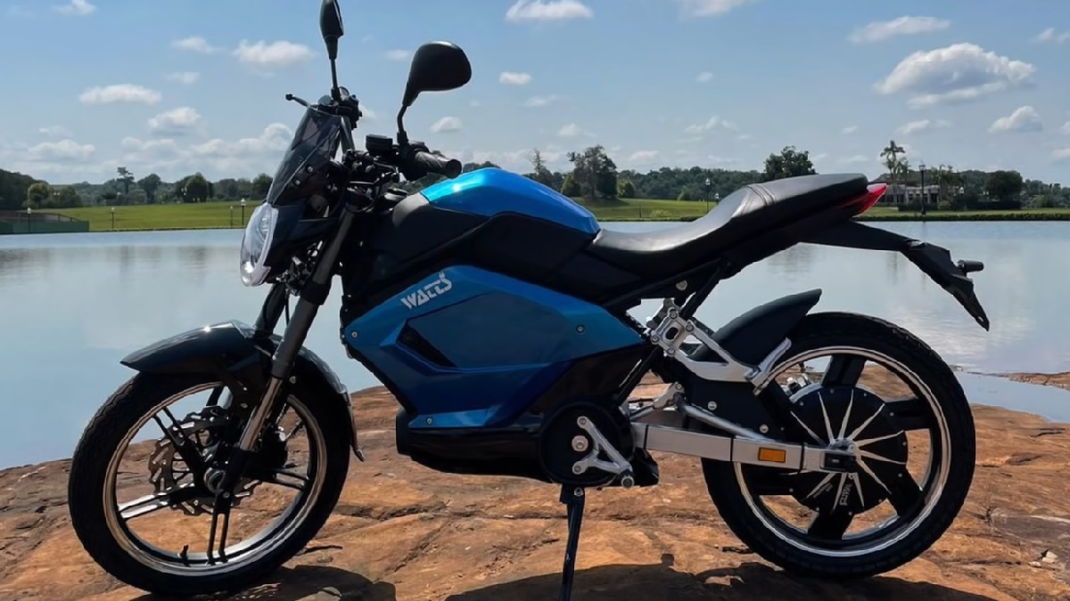 Watts W125 azul e preta de lado, em uma preda, com um lago ao fundo