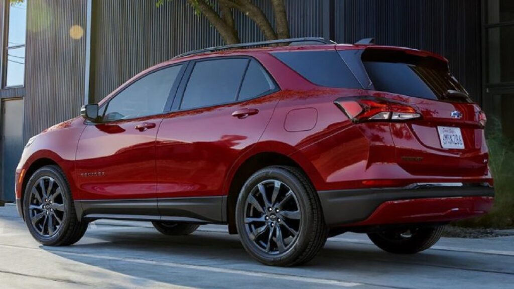 Lateral traseira Chevrolet Equinox RS 2023 vemelho, com detalhamento preto rodando por uma cidade