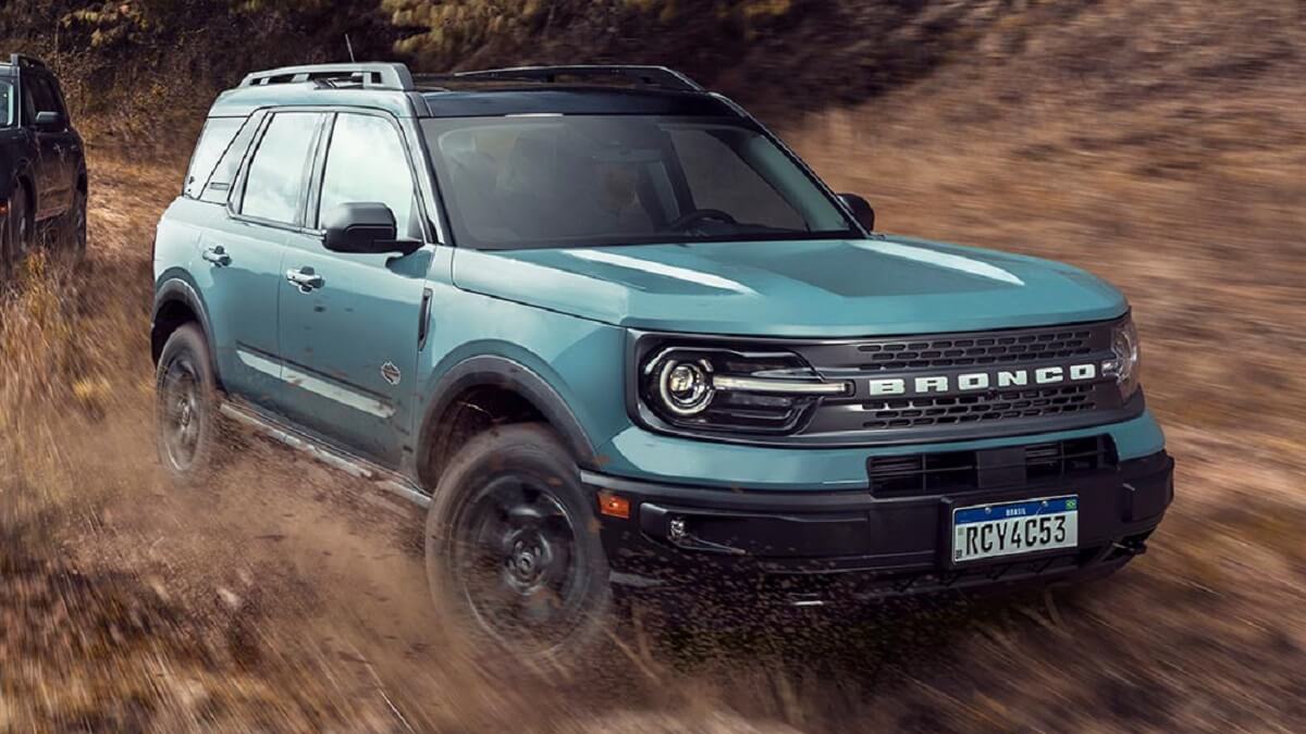 Lateral frontal de uma Bronco 2023 na cor azul rodando pela lama