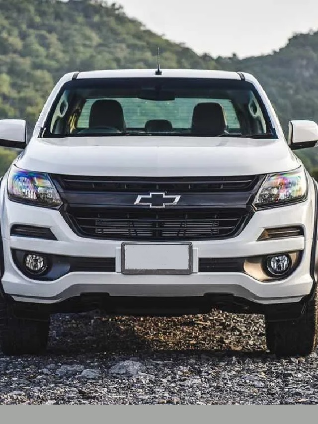 Frente de uma Chevrolet 2023 s10 branca, com partes pretas em uma estrada de pedras