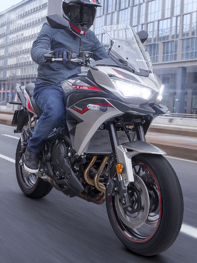 Motociclista em uma Kawasaki Versys 650 2022 prata rodando por uma avenida na cidade.