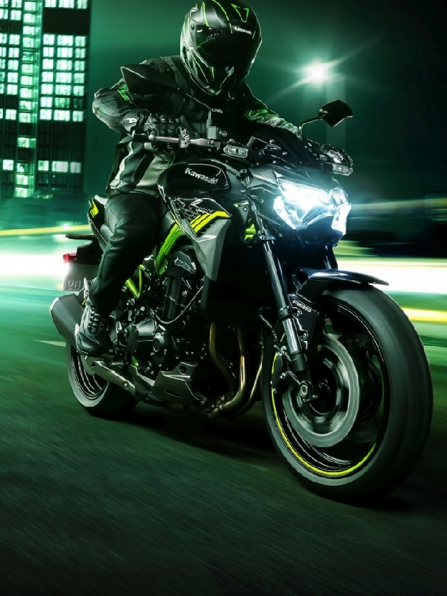 Lateral frontal de um piloto em uma Kawasaki Z 900 2022 verde, rodando a noite em uma cidade.