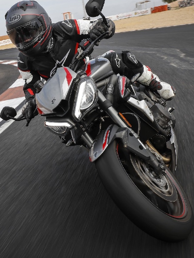 Motociclista em uma Triumph Street Triple 765 2022 prata, com partes pretas e detalhes vermelho fazendo uma curva em uma pista