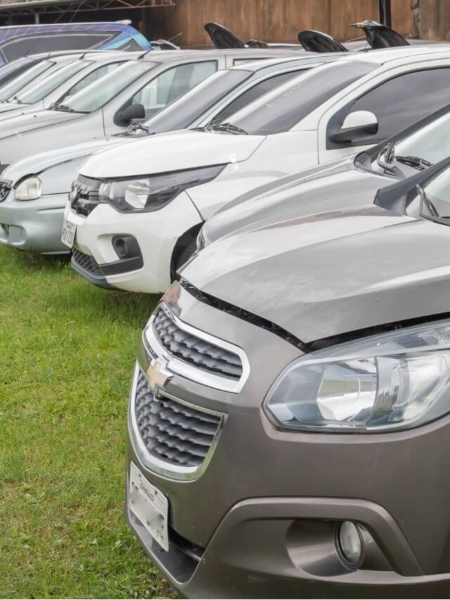 Frente de vários carros de leilão que estão parados no pátio