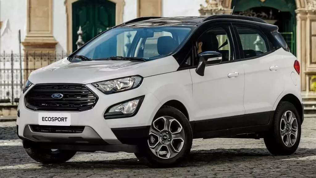 lateral frontal de uma Ford EcoSport 2023 na cor branca com partes pretas estacionada em uma praça.