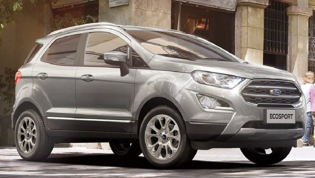 lateral frontal de uma Ford EcoSport 2023 na cor cinza estacionada em uma praça.