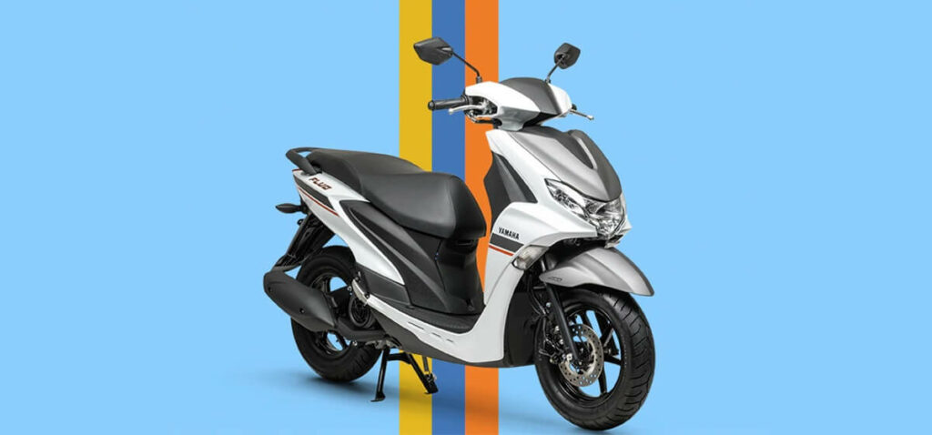 Yamaha Fluo 125 ABS 2023, na cor prata com o banco na cor preto. Contendo um fundo azul, e totalmente colorido.