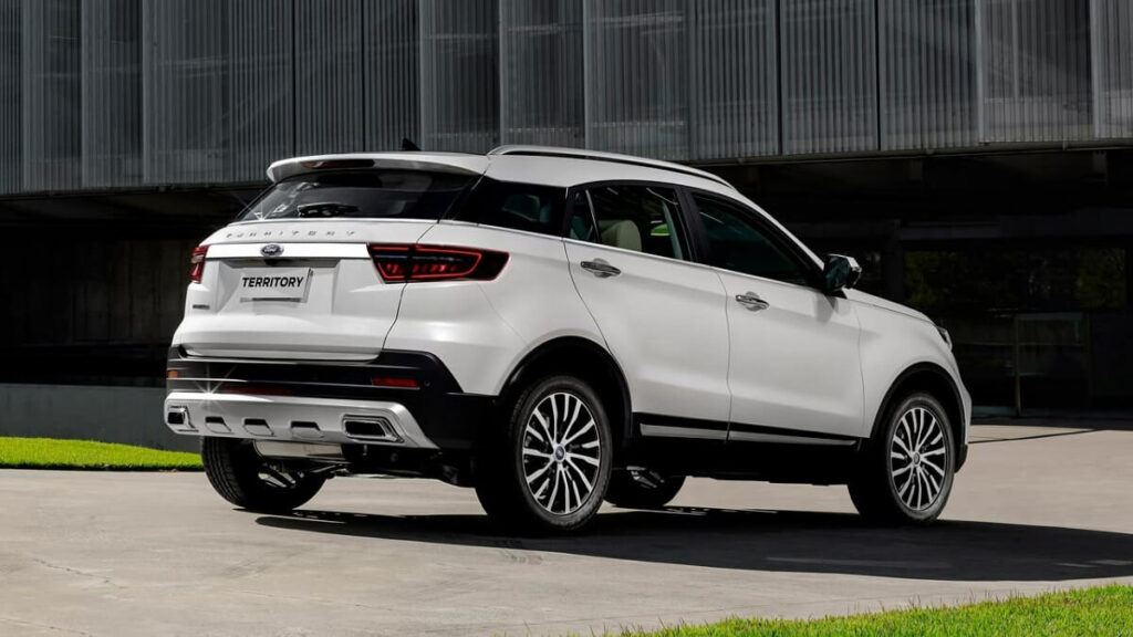 Lateral traseira de uma Ford Territory 2023 na cor branca estacionada próxima a um gramado.