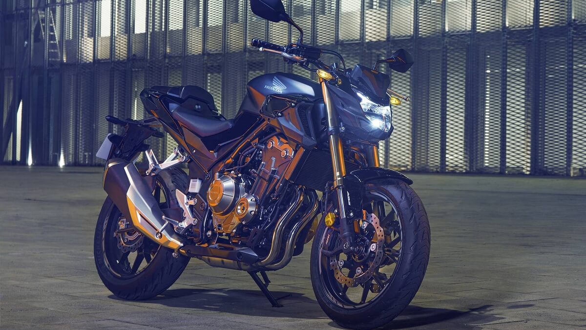 Lateral frontal de uma CB 500F 2023 na cor preta com partes dourada em uma noite