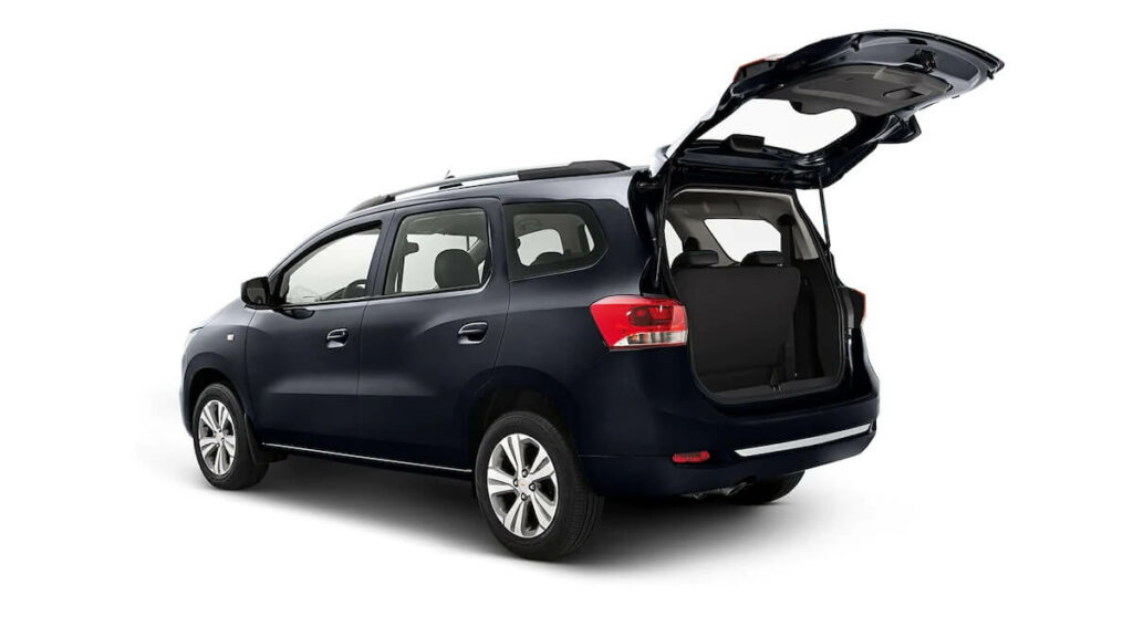 Lateral traseira de uma Chevrolet Spin 2023 na cor preta, estacionado com o porta-malas aberto em um fundo branco.