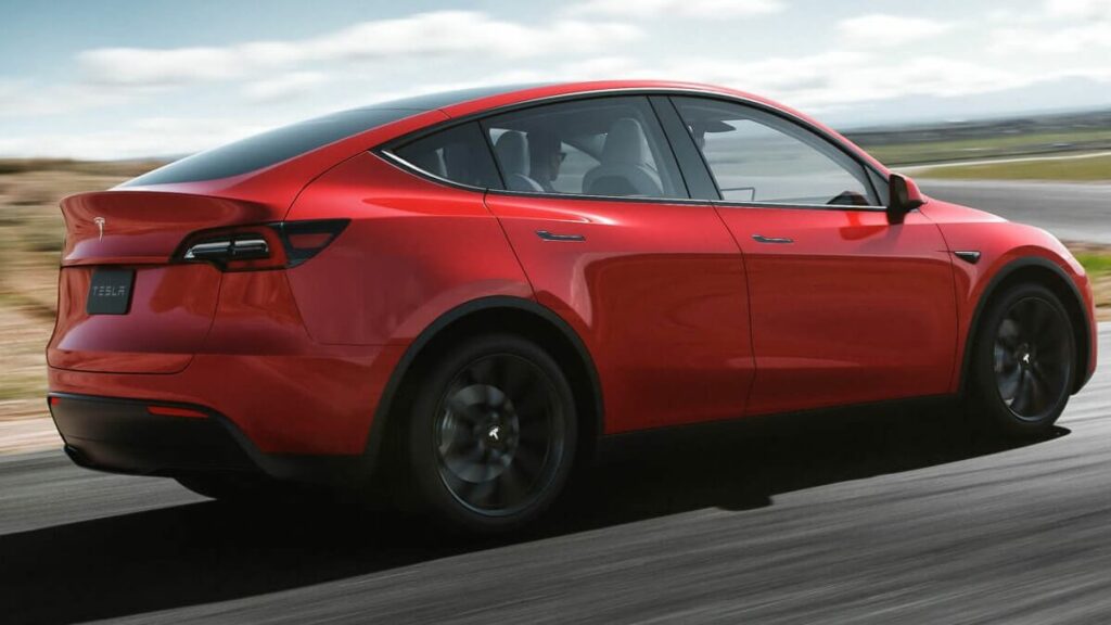 Traseira e lateral do Tesla Model Y 2022 na cor vermelho, andando no asfalto