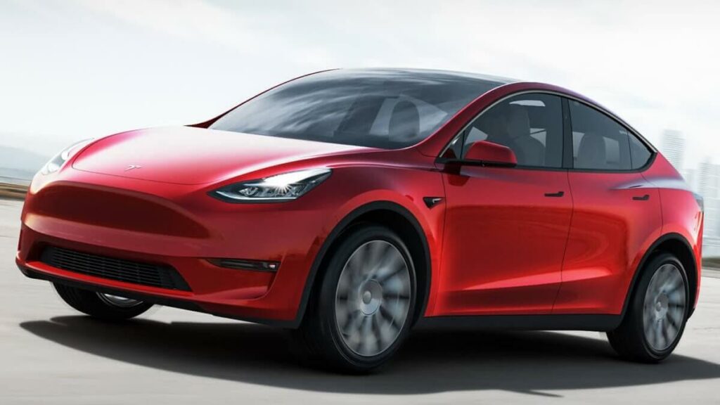 Frente e lateral do Tesla Model Y 2022 na cor vermelho, andando na estrada