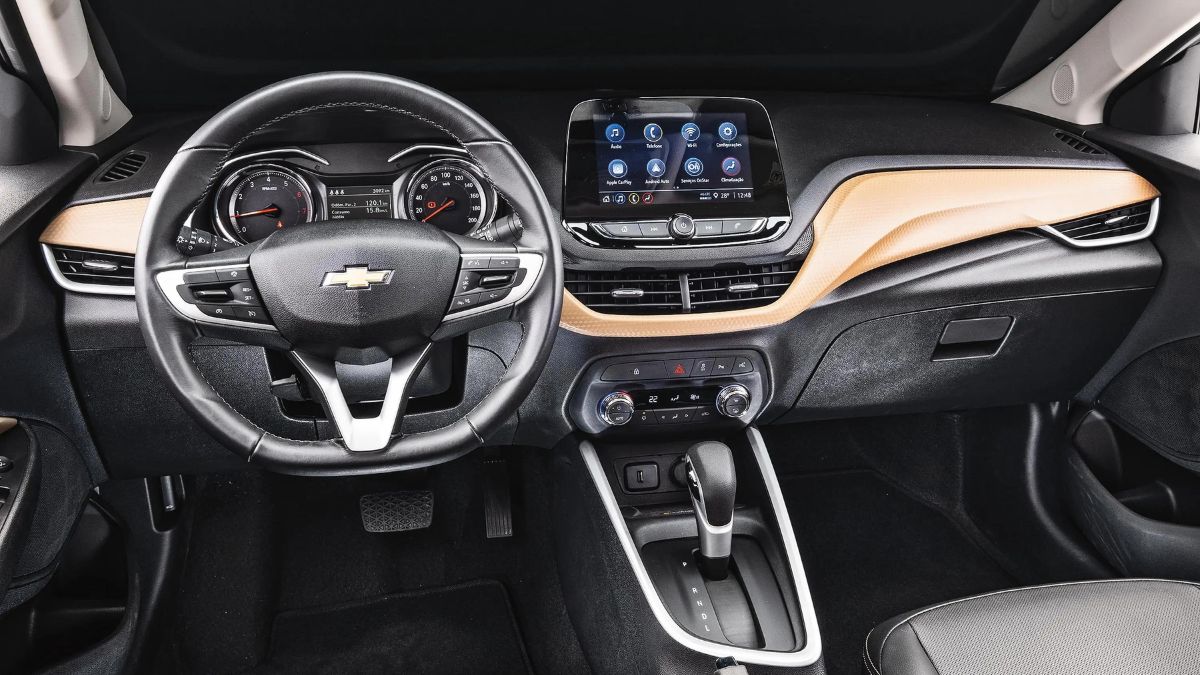 Interior do Onix Plus 2023, predominantemente preto, com detalhes em laranja no console