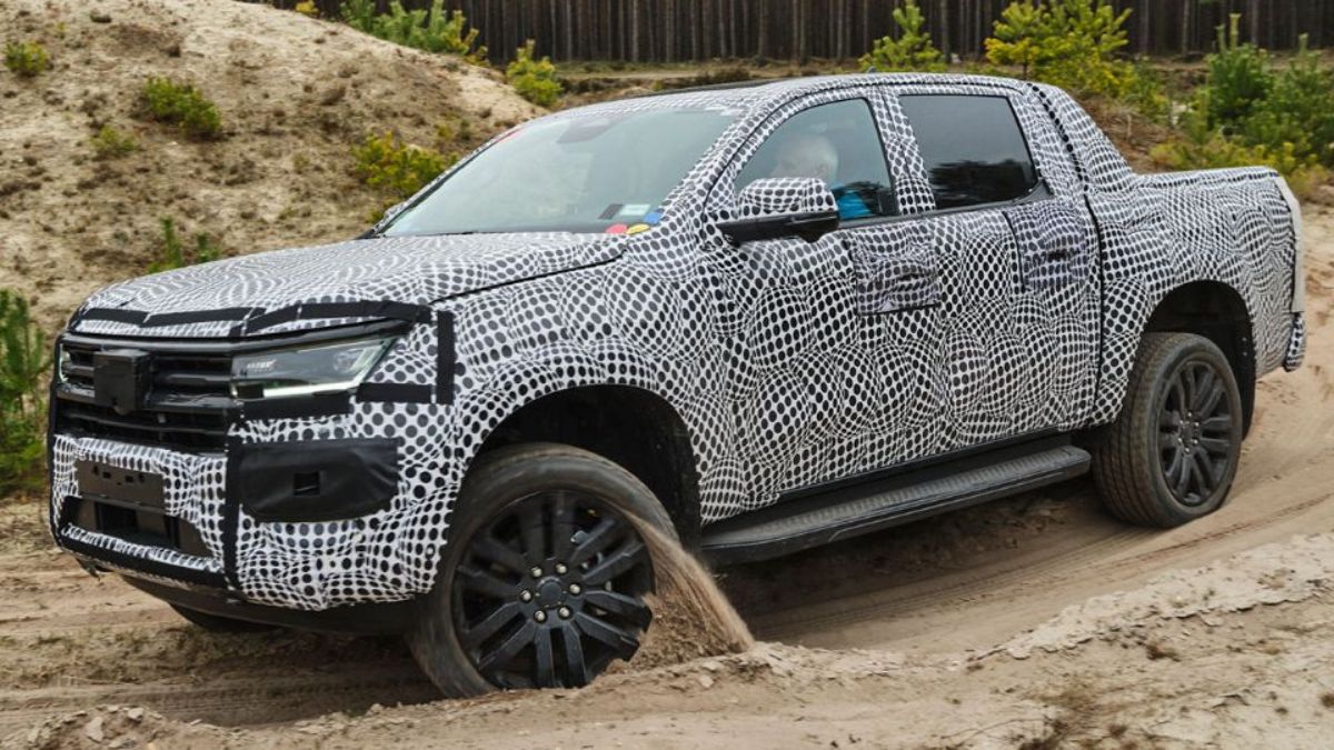 Lateral da Amarok 2023, camuflada em estrada de areia