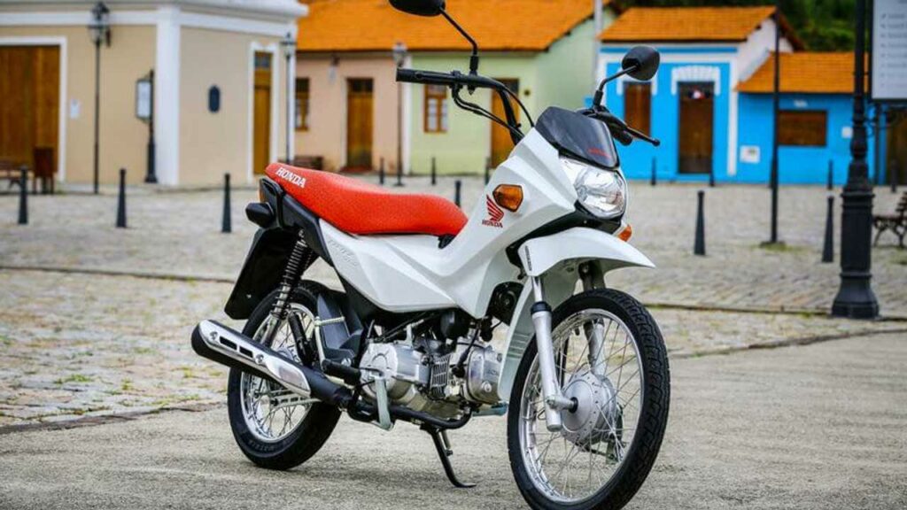 Honda POP 110i 2023 esta parada nas ruas e sua cor é branca com assento vermelho