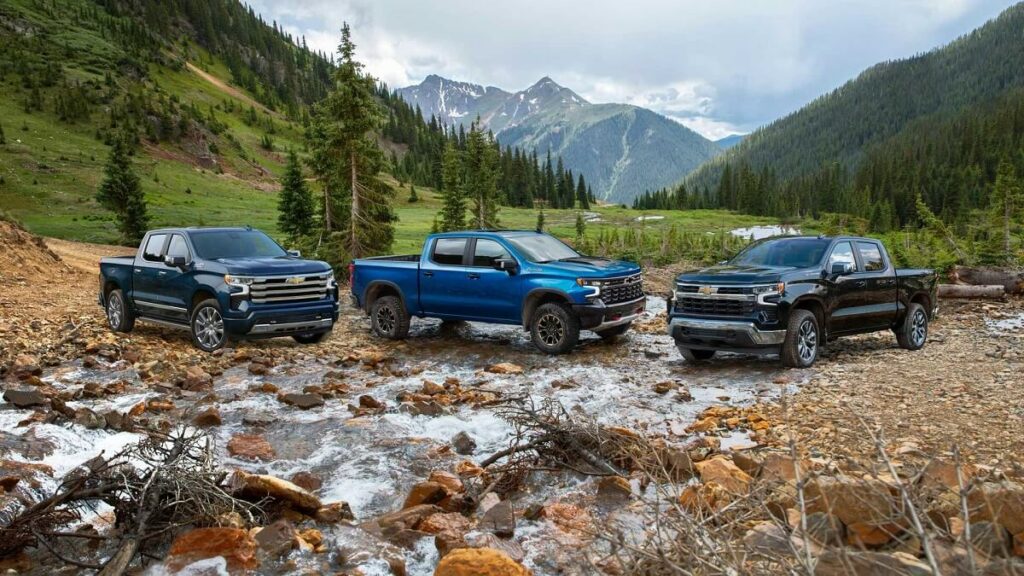 Foto de três picapes Silverado em uma paisagem, as três estão estacionadas uma no lado da outra