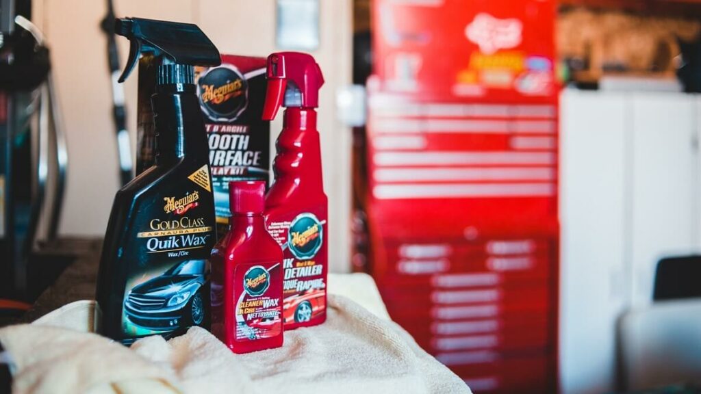 Diversos produtos de limpeza sobre um pano de cor clara m uma lavação de carros