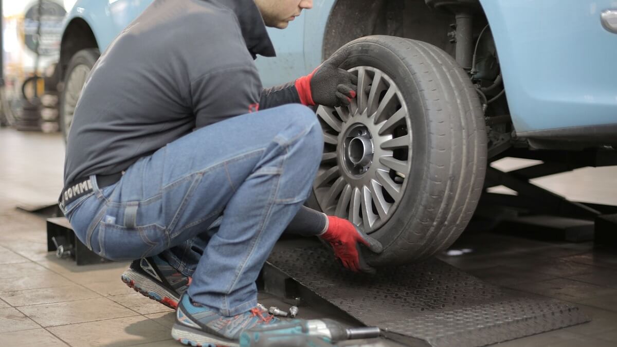 Homem trocando os pneus de um carro azul