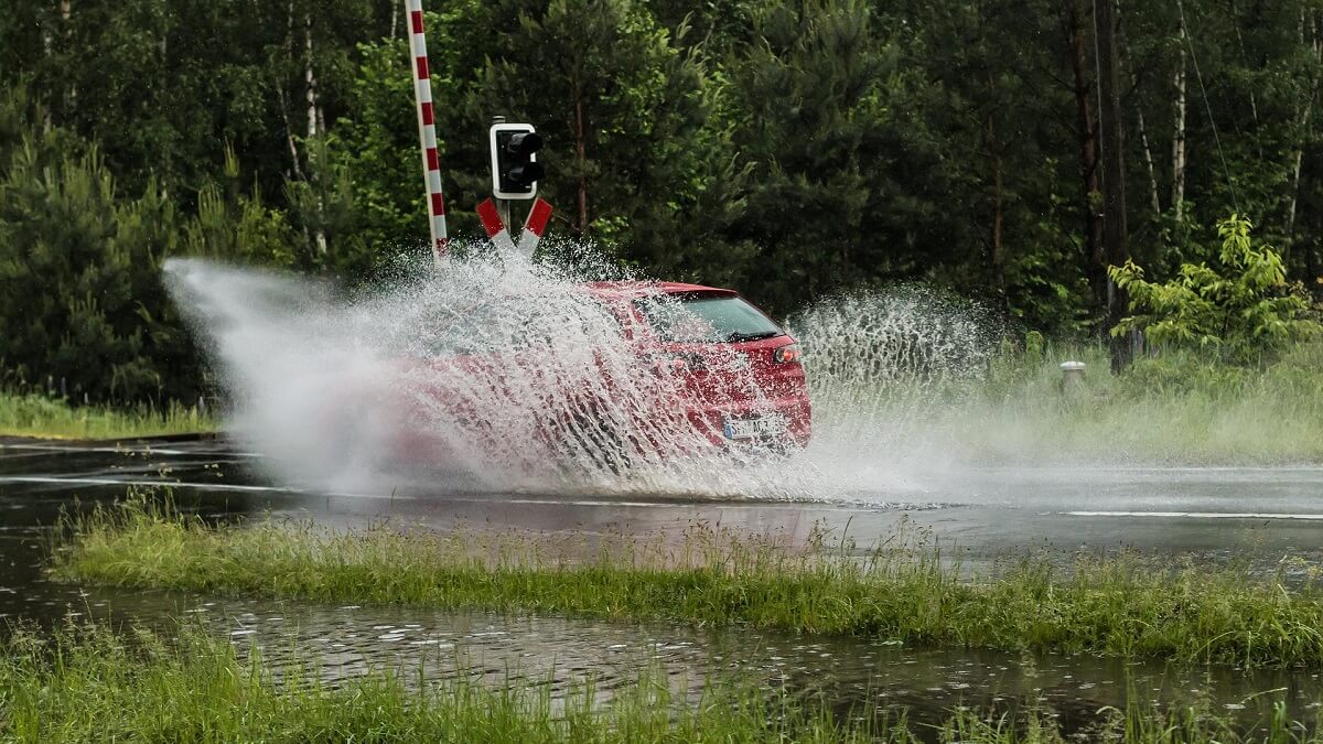 Carro passando por grande poça de água.