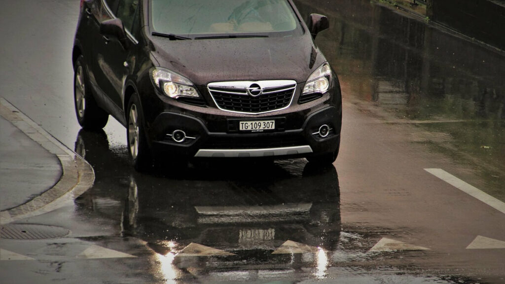 Carro parado em frente a uma poça de água.