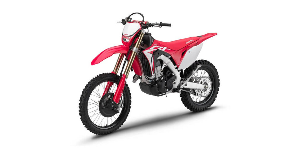 Foto frontal da CRF 450 X 2023 vermelha estacionada de lado