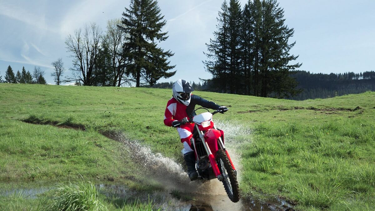 Foto de uma pessoa praticando moto trilha com uma CRF 450 X 2023 vermelha