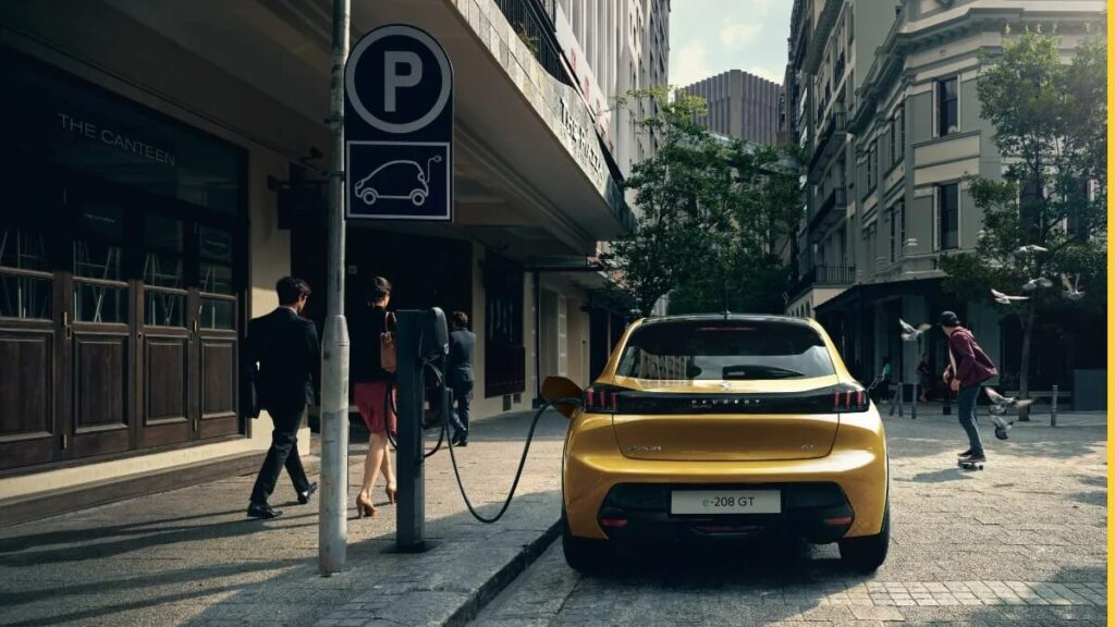 Foto de um e-208 2023 carregando ao lado de um carregador super-rápido