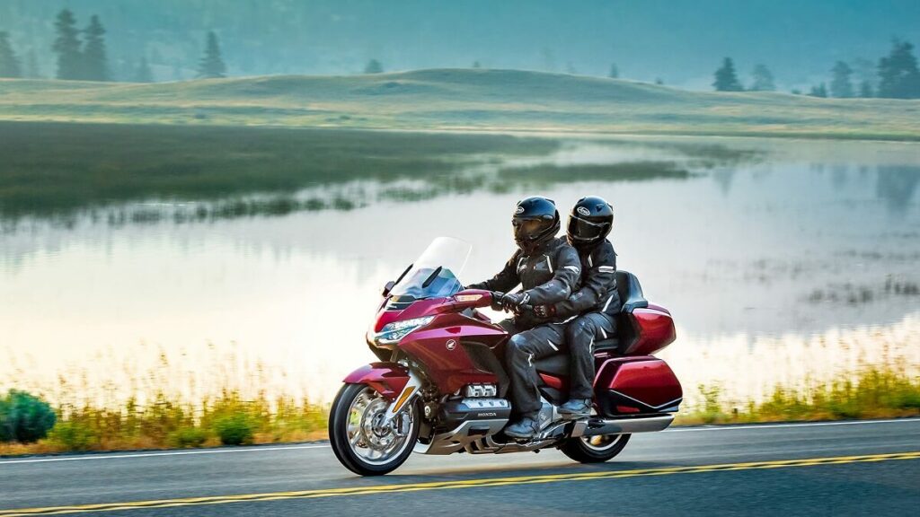 Foto de duas pessoas em cima de uma Gold Wing Tour 1800 2023, eles estão pilotando ao lado de um lago