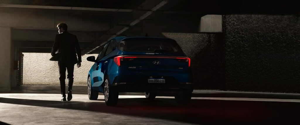 Foto traseira de um HB20 2023 E tem uma pessoa andando ao lado