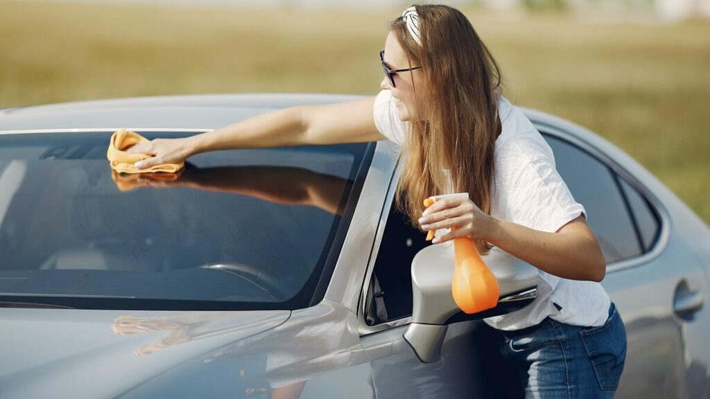 Mulher higienizando os vidros do veiculo