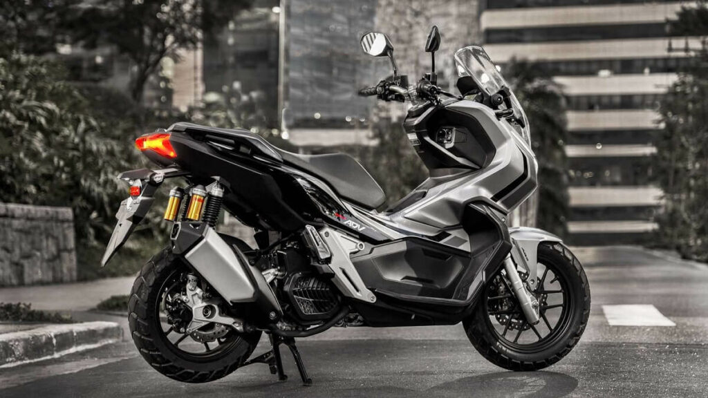 Foto lateral de uma Honda ADV 2023 prata estacionada em uma rua