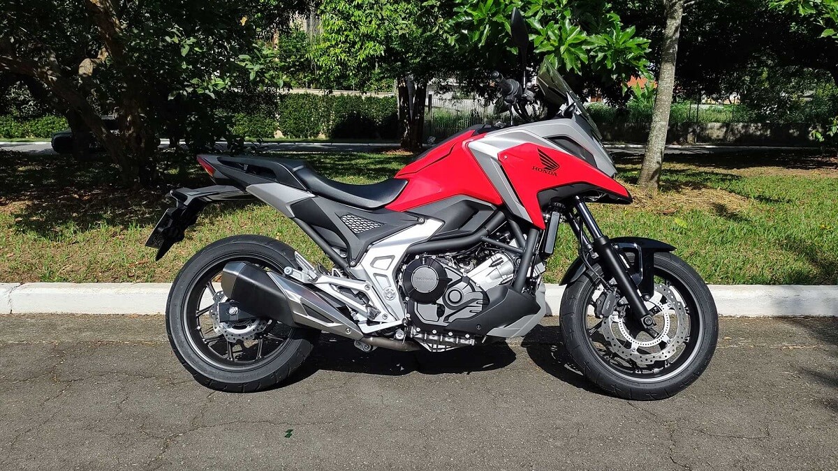 a foto da NC 750X 2023 mostra toda sua carenagem e estilo único, a moto esta estacionada de lado na rua