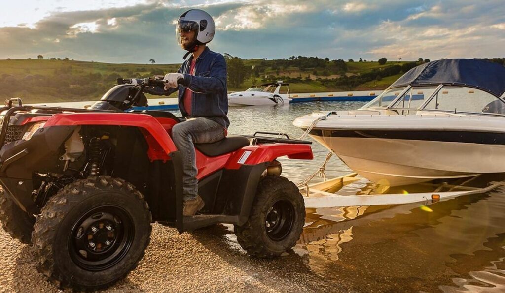 Foto de uma TRX 420 Fourtrax 2023 vermelha puxando um Jetski