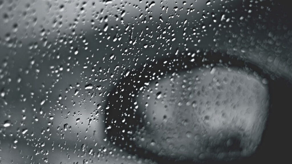 Foto focada no vidro do carro durante um dia chuvoso.