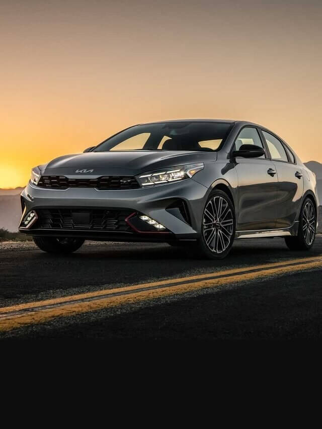 Kia Cerato 2023 andando no asfalto, possui um belo por de sol de fundo