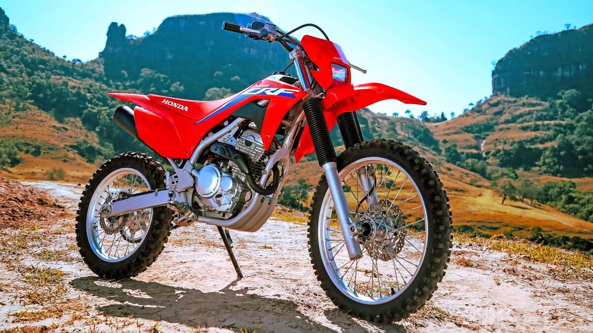 Foto lateral de uma CRF 250 F 2023 vermelha em uma paisagem