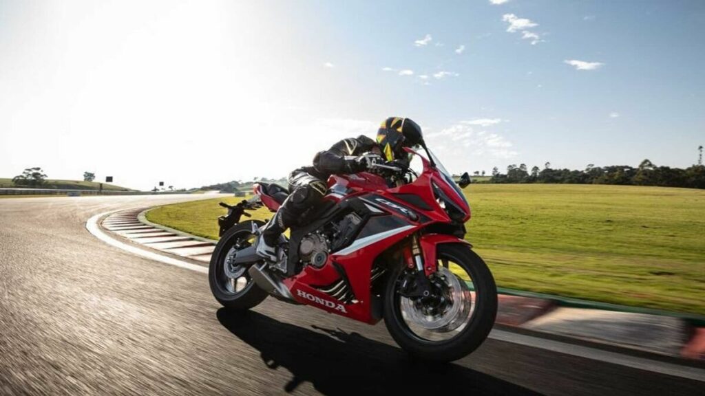 Foto lateral de uma pessoa correndo com uma CBR 650 R 2023 em uma pista