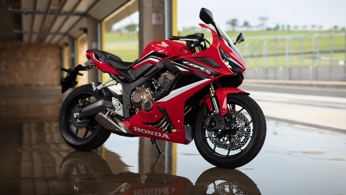 Foto lateral de uma CBR 650 R 2023 vermelha estacionada em uma garagem