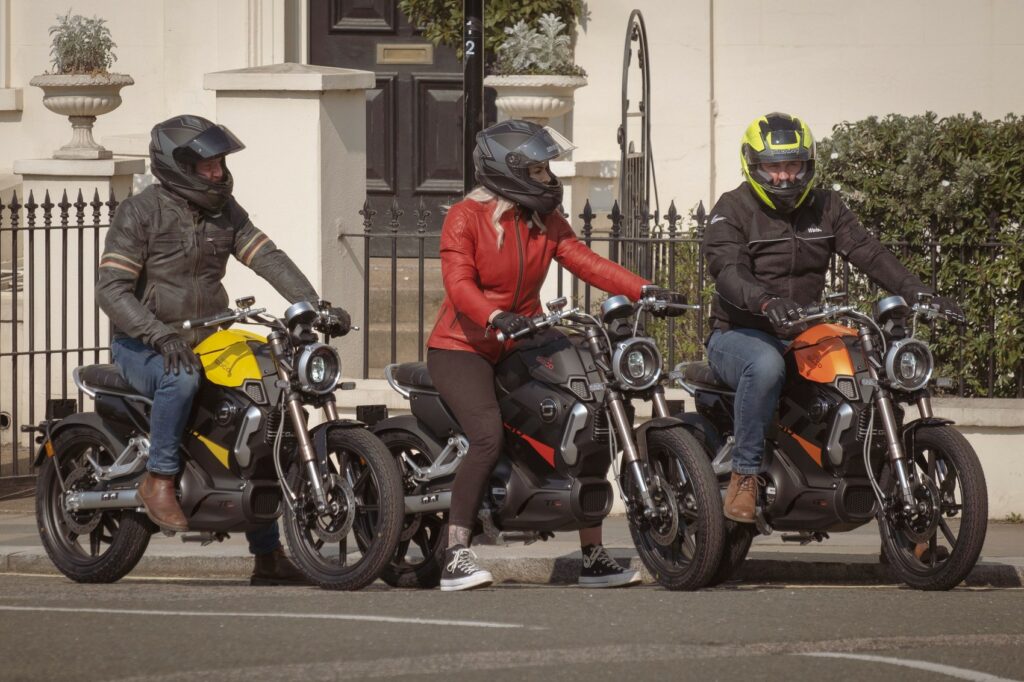 3 pessoas montadas em 3 motos TC MAX 2023 mas cores amarela, cinza escuro e laranja.