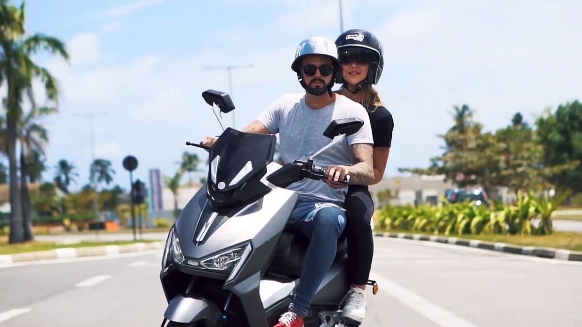 Foto de um casal andando em cima de uma EV1 Sport 2023 cinza