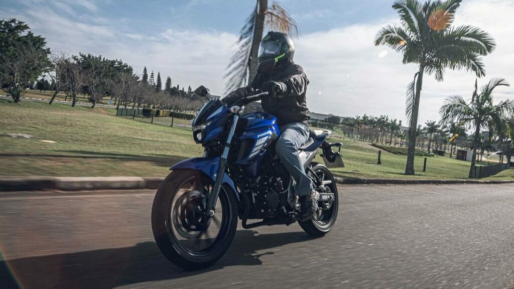 Foto de uma pessoa andando de 250 Fazer 2023 azul em uma estrada